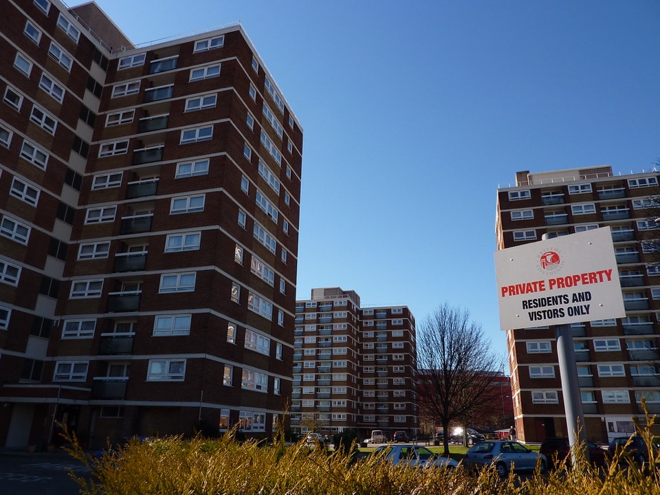 A tall brick block of flats with a balcony outside every window