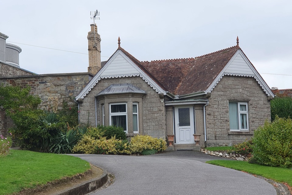 A stone bungalow behind a curved lawn and driveway