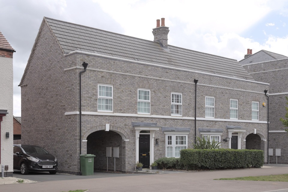 A modern brick semi-detached house with a plain pitched roof and two dark front doors